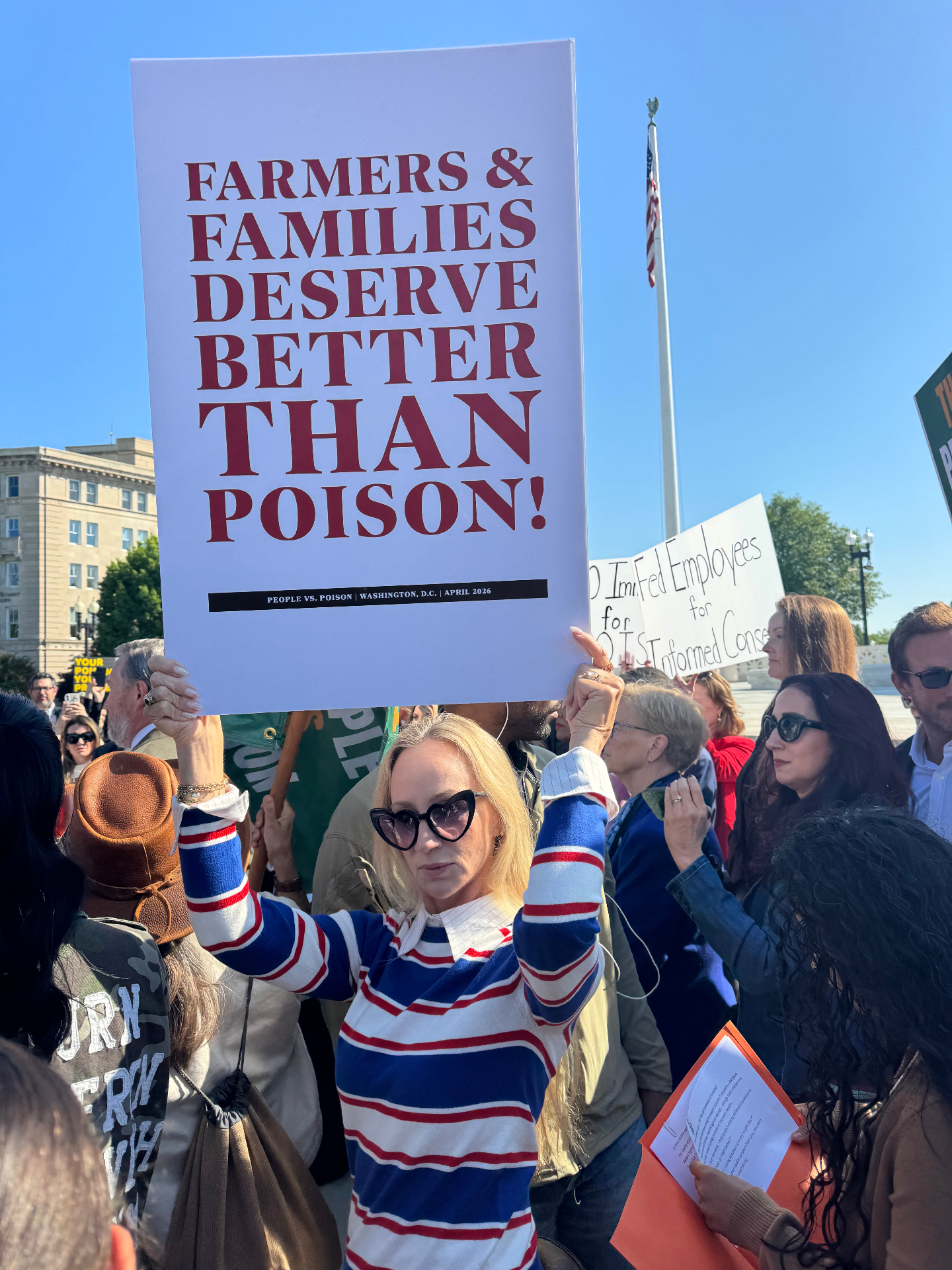 Woman holding a sign reading 'Farmers & Families Deserve Better Than Poison!'