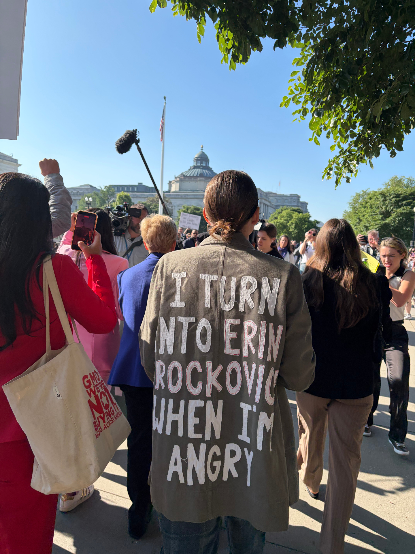 Protester in a jacket reading 'I turn into Erin Brockovich when I'm angry'